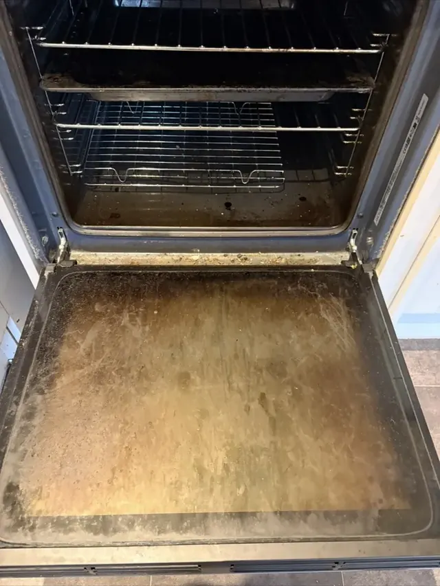 Greasy oven door glass and base before cleaning